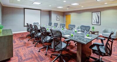 Boardroom with long table, chairs, and presentation screen