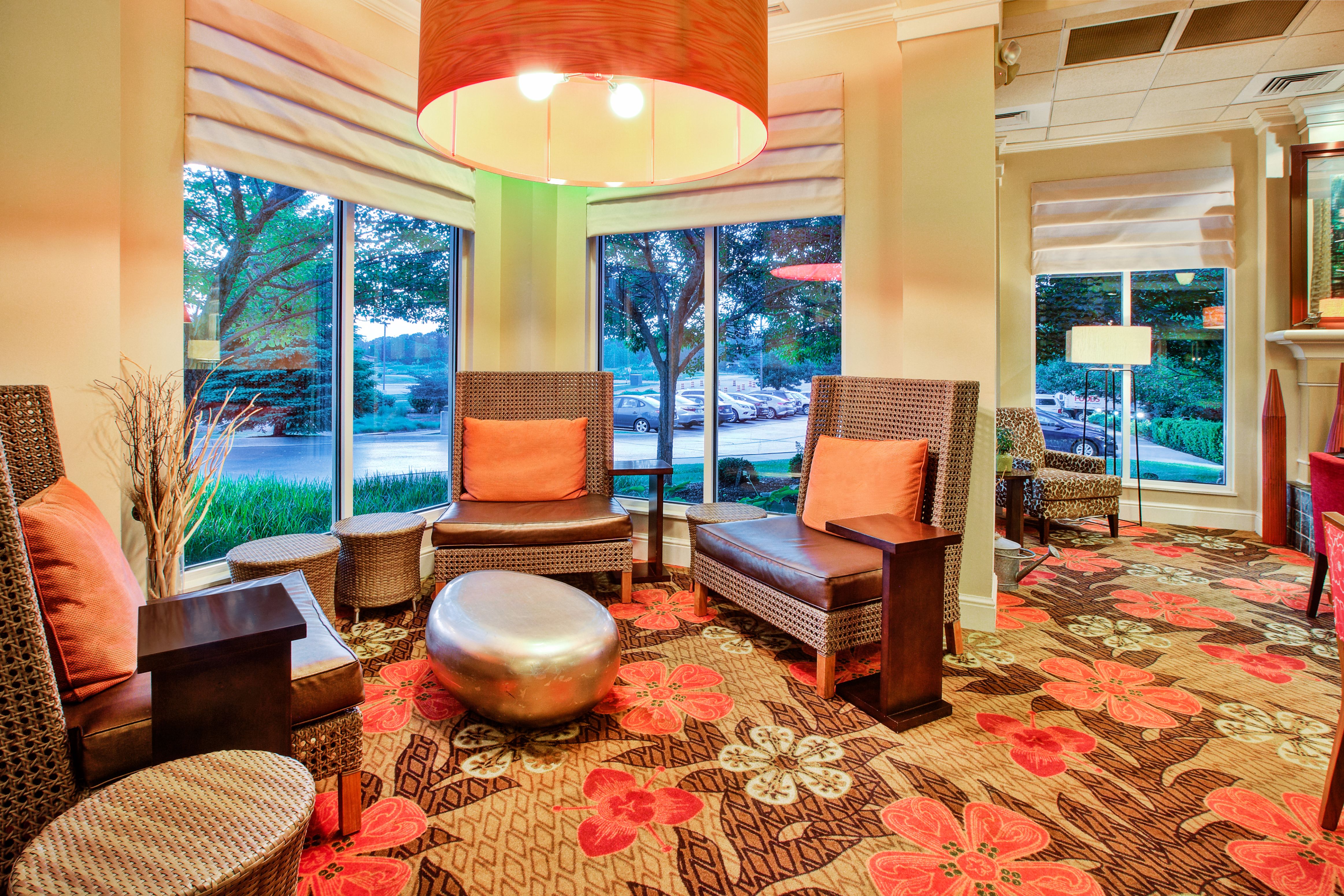 Lobby seating area with lounge chairs, ottoman, and windows with outdoor view