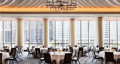 Naturally lit Ballroom Set with Round Tables Showing Designed Ceilings and Columns Near Floor to Ceiling Windows