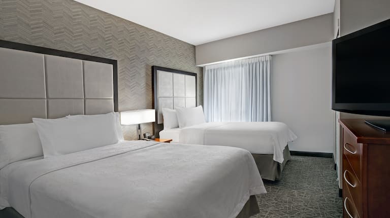 guest room with two beds television and window