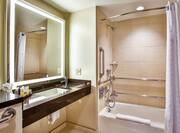 Accessible bathroom with bath, sink and mirror