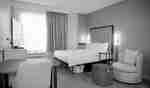 Studio suite with one queen bed, a work desk, open door to bathroom and entry in the background.