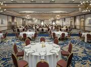 Spacious grand ballroom featuring banquet tables with beautiful linens, table settings, and candles.