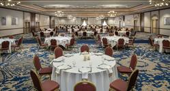 Spacious grand ballroom featuring banquet tables with beautiful linens, table settings, and candles.
