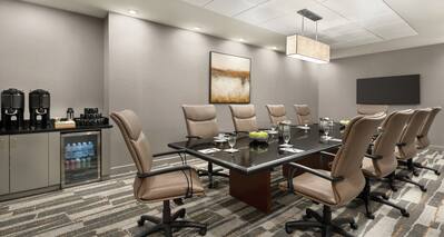 Spacious meeting room featuring large boadroom table, TV, and refreshments area.
