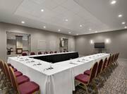 Large conference room fully set up with u shape table, notepads and pens, glasses, and TV.