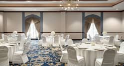 Spacious grand ballroom featuring banquet tables fully decorated and set for a wedding.