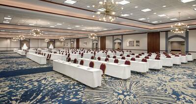 Spacious grand ballroom fully set in classroom style with long tables and ample seating.