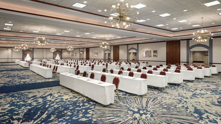 Spacious grand ballroom fully set in classroom style with long tables and ample seating.
