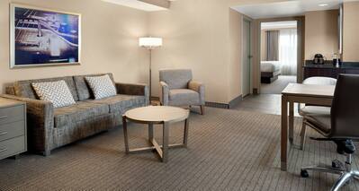 Spacious corner suite featuring lounge area with sofa, work desk, and wet bar.