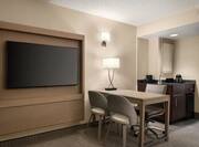 Spacious lounge area in suite featuring TV, work desk, and wet bar.