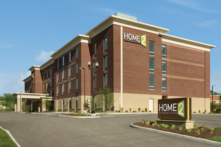 Daytime View of Hotel Exterior with Signage, Landscaping and Parking