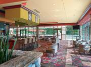 Rocky River lounge bar with dining tables, chairs, and floor-to-ceiling windows with outdoor view