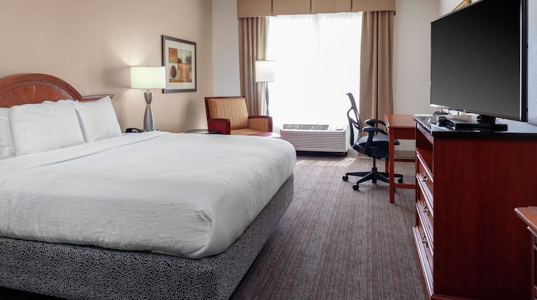 特大床,配有电视、书桌和座椅。