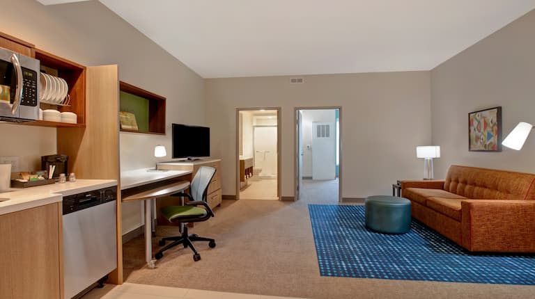 a guest suite lounge area with work desk and television