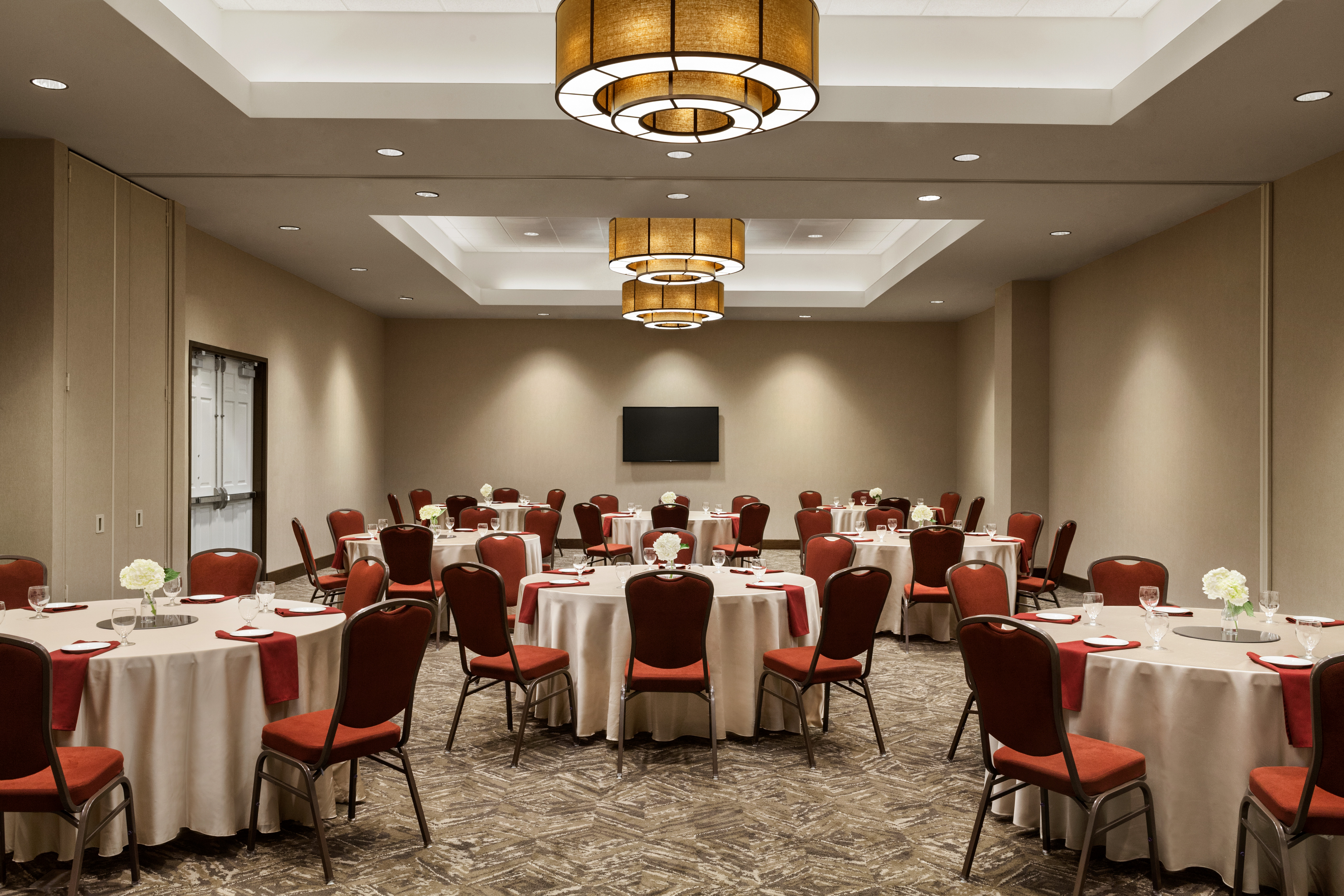 Spacious Ballroom Banquet Setup with Roundtables, Chairs and Wall Mounted HDTV