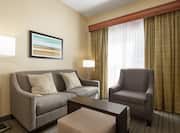 Bright lounge area in accessible suite featuring comfortable sofa and arm chair.