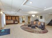 Spacious hotel lobby featuring welcoming front desk, comfortable seating area, and complimentary coffee station.