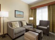 Bright lounge area in one bedroom suite featuring comfortable sofa and arm chair.