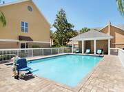 Beautiful outdoor pool featuring convenient accessible chair lift and shaded lounge area.