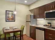 Spacious in-suite kitchen featuring dining table, full size fridge, and induction cook-top.