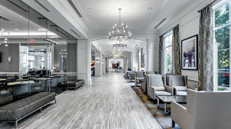 Lobby lounge area with soft chairs, soft benches, coffee tables, and floor-to-ceiling windows with outdoor view
