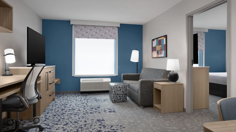 Suite living room with sofa, TV, work desk and storage space