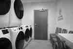 Çamaşır makinesi, kurutma makinesi ve sandalyeler bulunan misafir çamaşır odası