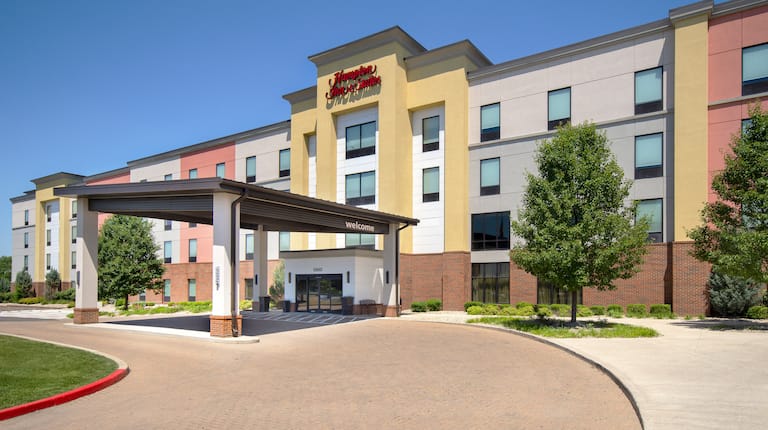 Hotel exteriors showing red, yellow, and white building with a covered drop off area.