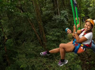 Man and woman ziplining in the jungle