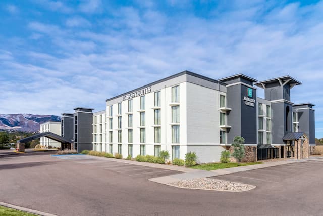 Exterior of hotel building at day time with blue sky and empty parking
