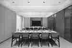 Meeting room with rows of tables, orange chairs, notepads, water bottles, and a wall-mounted display screen.