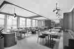 Hotel restaurant with modern tables, chairs, a banquette, hanging light fixtures, and large windows.
