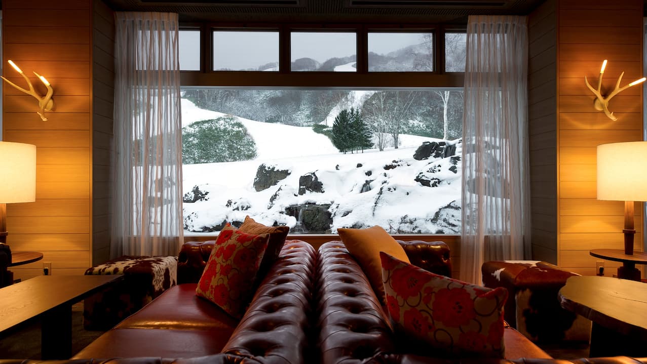 Restaurant seating area with couches, tables, and lamps, near large window