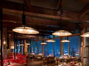 Limited Edition Grill restaurant with dining tables, chairs, dining amenities, and floor-to-ceiling windows with city view at night