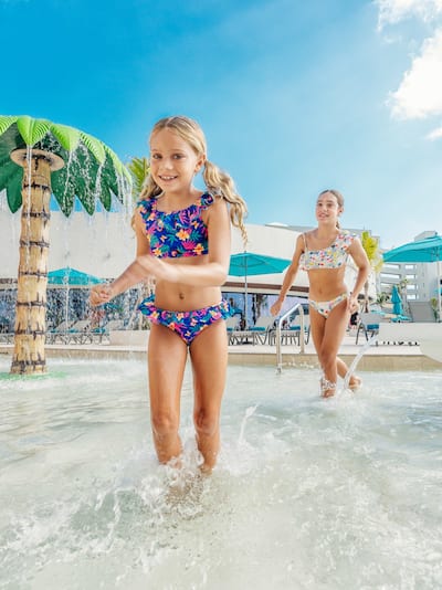 Young girls running through swimming pool with water features