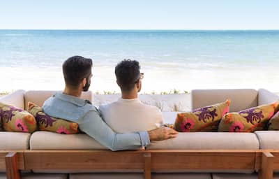 Two men sit next to each other and look at the ocean