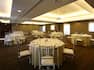 Place Settings on Round Tables With White Linens, Chairs, and Overhead Projector in Muya Room Set for Banquet