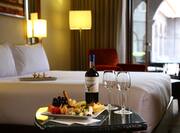 Appetizers and Wine Glasses on Room Service Tray by King Bed With View of Terrace