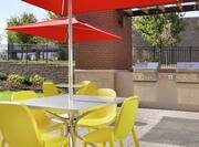 Outdoor patio with Grills and seating area with tables, chairs and parasols