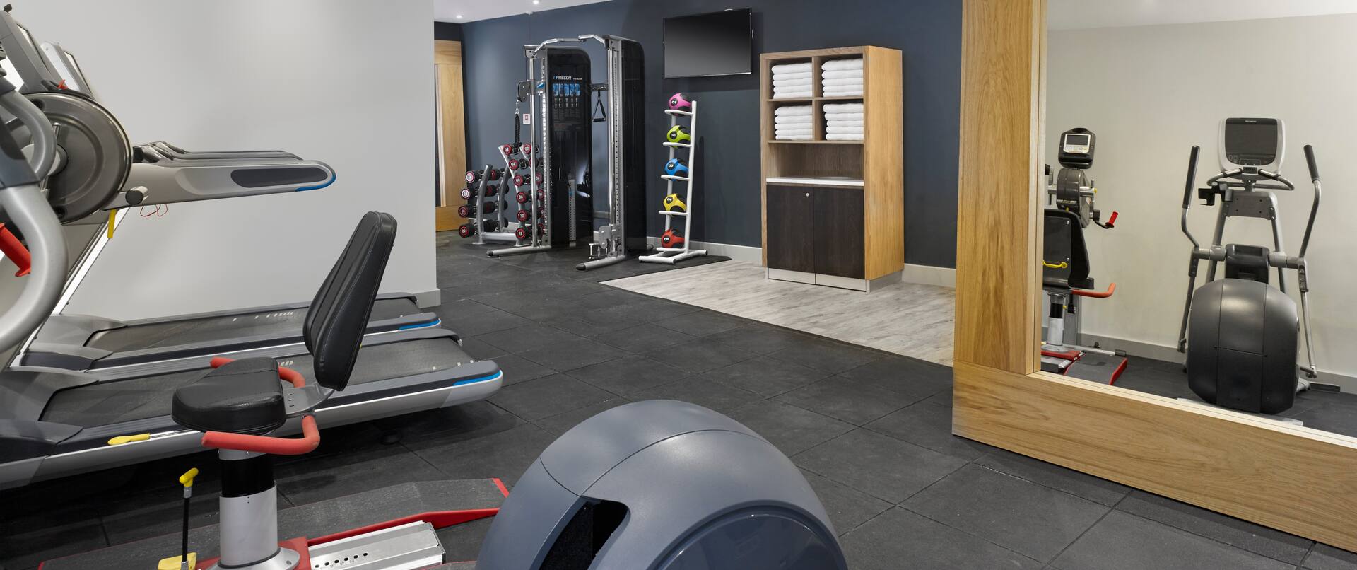 Large Mirror, Cardio Equipment, TOwel Station TV, Weight Balls, and Weight Machine in Fitness Suite