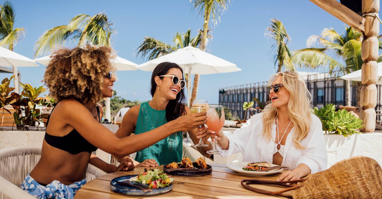 women at outdoor pool cabana with food and drinks