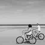 ビーチで自転車に乗るカップル