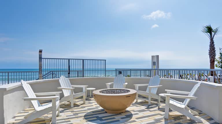 exterior patio with firepit and view of ocean