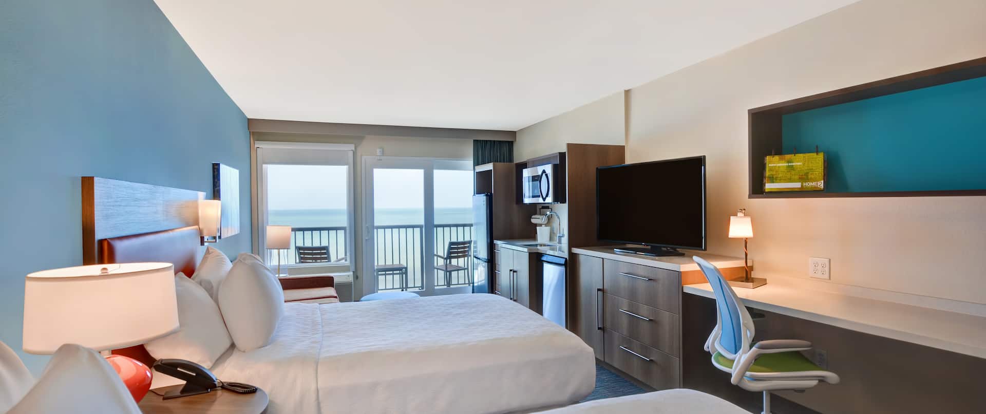 guest room with beds work desk and ocean view