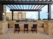 Exterior Patio with Lounge Area and Grills Underneath Pergola 