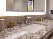 Detailed View of Brightly Lit Vanity Mirror Above Sink With Toiletries, and Amenities