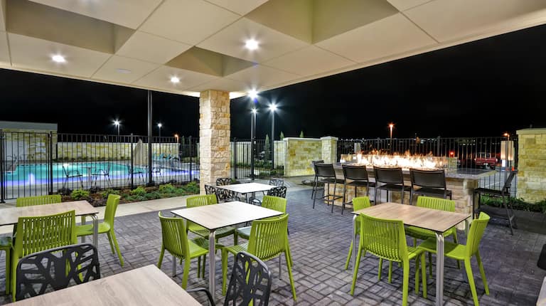 Home2 Suites Outdoor Patio with Tables, Chairs, Fire Pit, and Exterior Pool View
