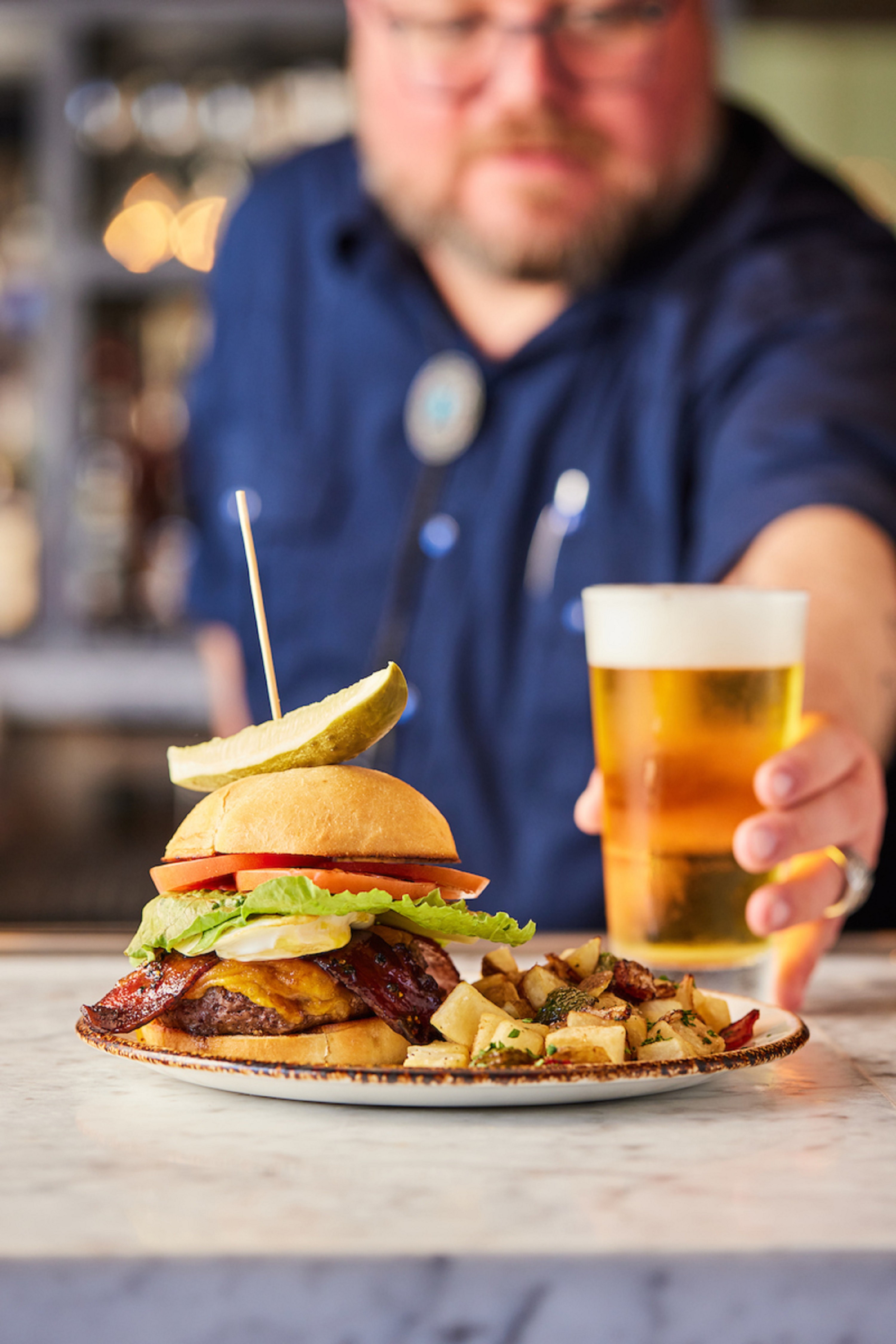 a Man with a Plate with Burger and Fries and a Glass of Beer at Elm Street Cask and Kitchen