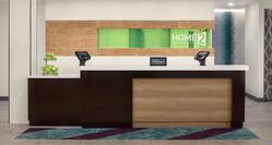 Welcoming front desk in hotel lobby featuring hilton honors sign, lowered accessible desk, and green apples.
